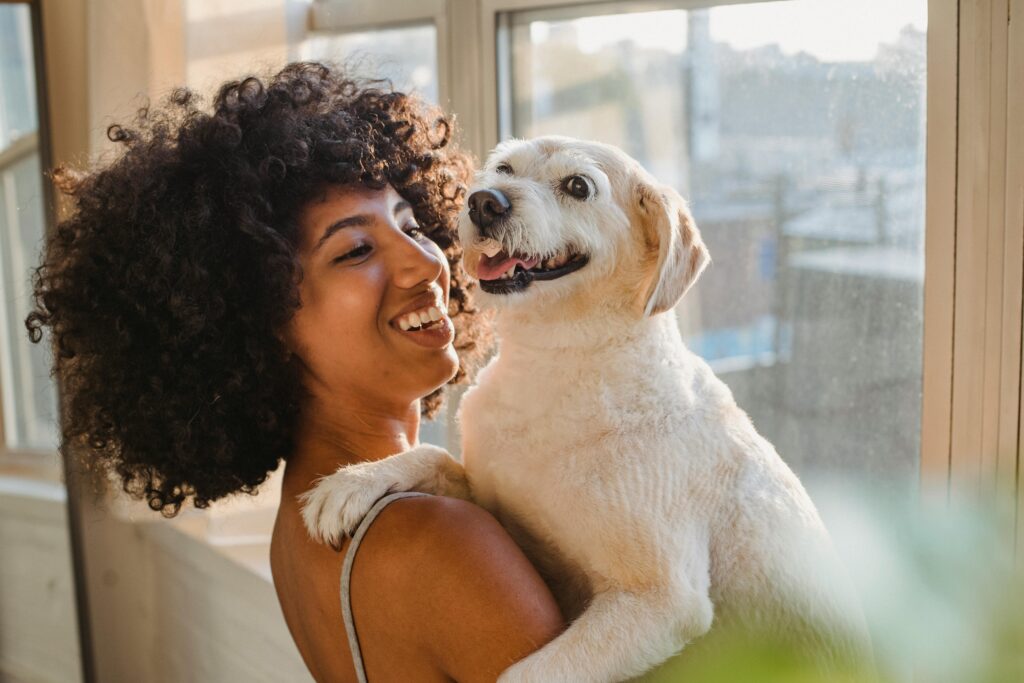 Eine Frau hat ihren Hund halb im Arm und lächelt glücklich