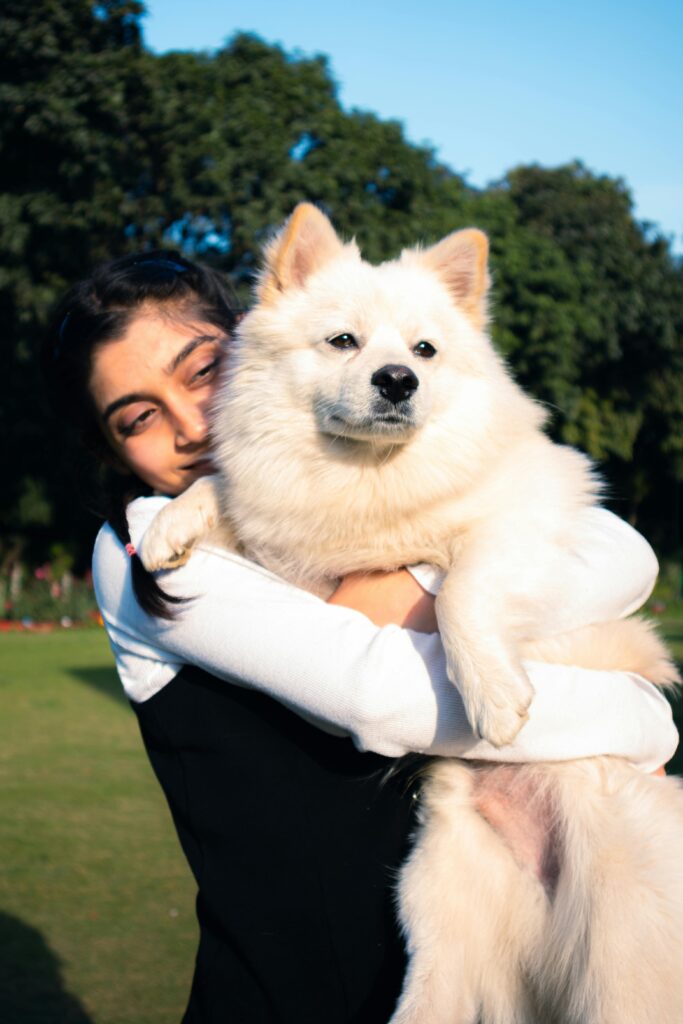 Eine Frau hat ihren Hund halb im Arm und lächelt glücklich