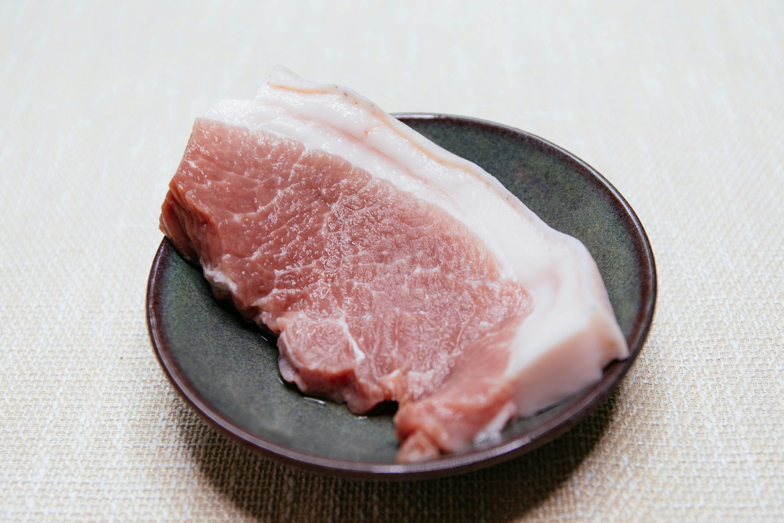 Stück Schweinefleisch roh auf einem schwarzen Teller
